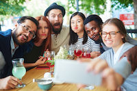 Un groupe d'amis qui prend une photo en faisant des grimaces hommes, femmes, cocktails, téléphone, grimaces
