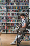un étudiant assis sur l'escalier de la bibliothèque étudiant, bibliothèque, livres, ordinateur, escalier, chaise