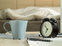 Une tasse et un réveil sur un bureau réveil tasse stylo lit cahier bureau